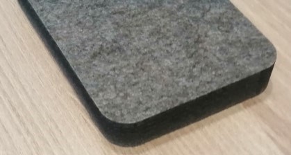 Superficie textil gris sobre una base negra, con bordes redondeados.